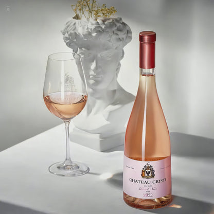 Sticla Chateau Cristi Pinot Noir Rose 2022 langa un pahar de vin rose, pe fundal bust clasic alb
